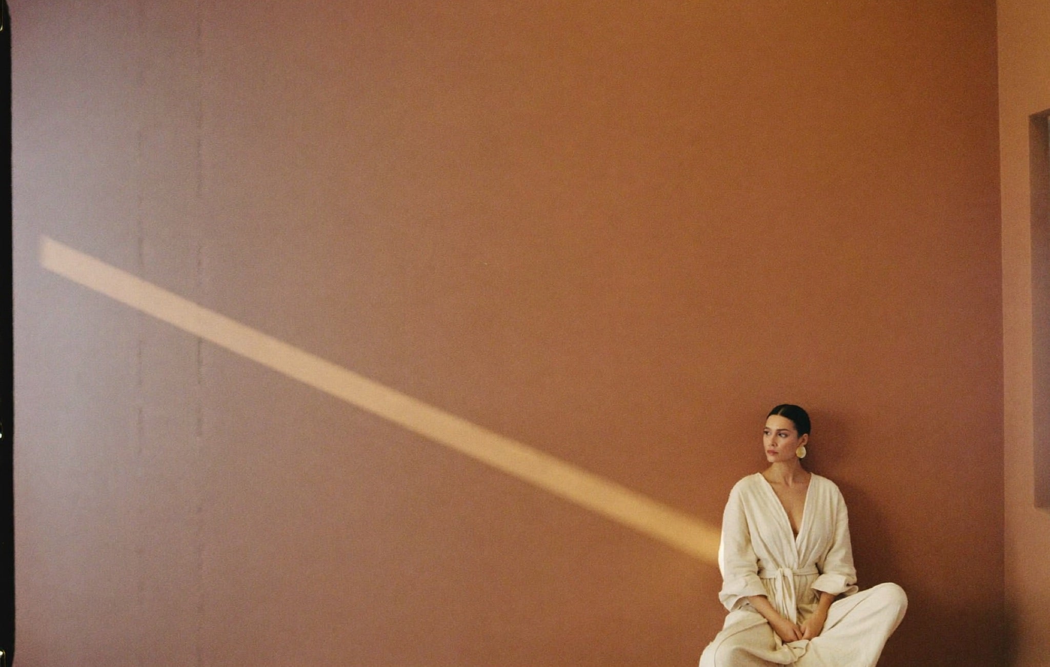 A calm seated figure beneath a sweep of morning light